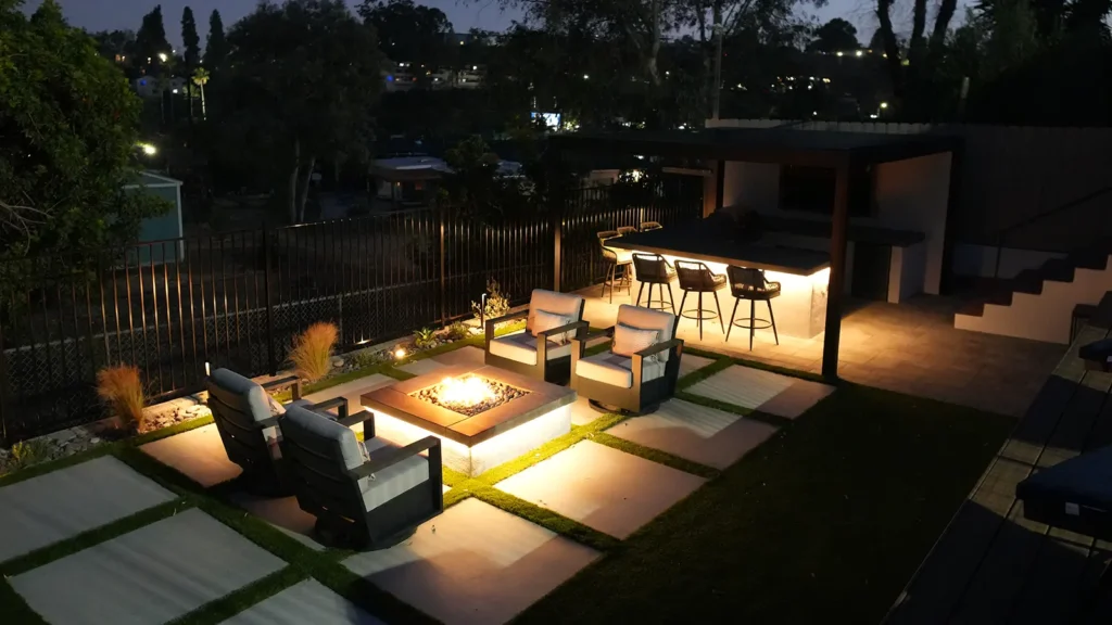 Backyard with outdoor kitchen, TV wall and fire pit lounge in San Diego